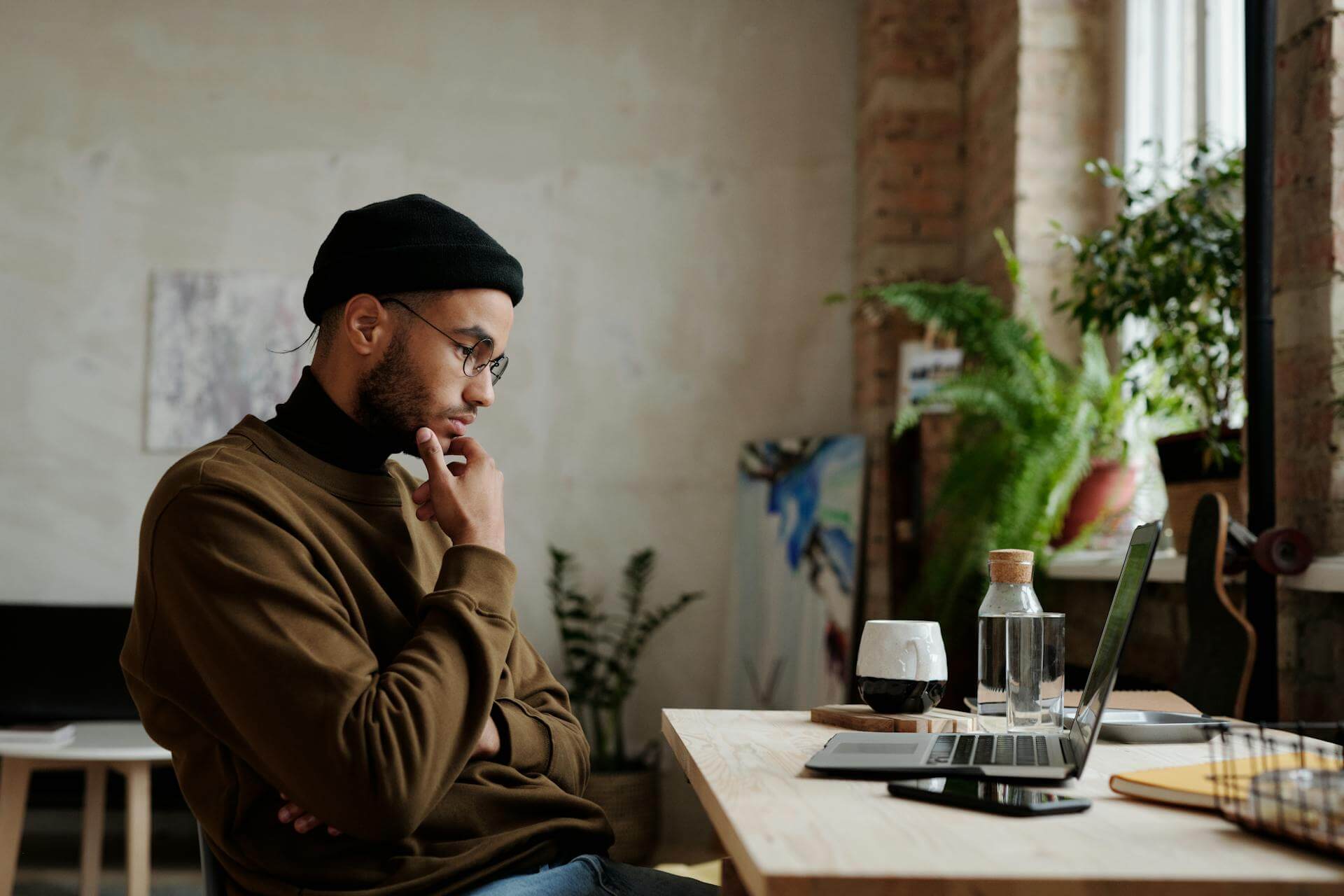 Small business owner thinking while comparing options on a laptop in a quiet cafe