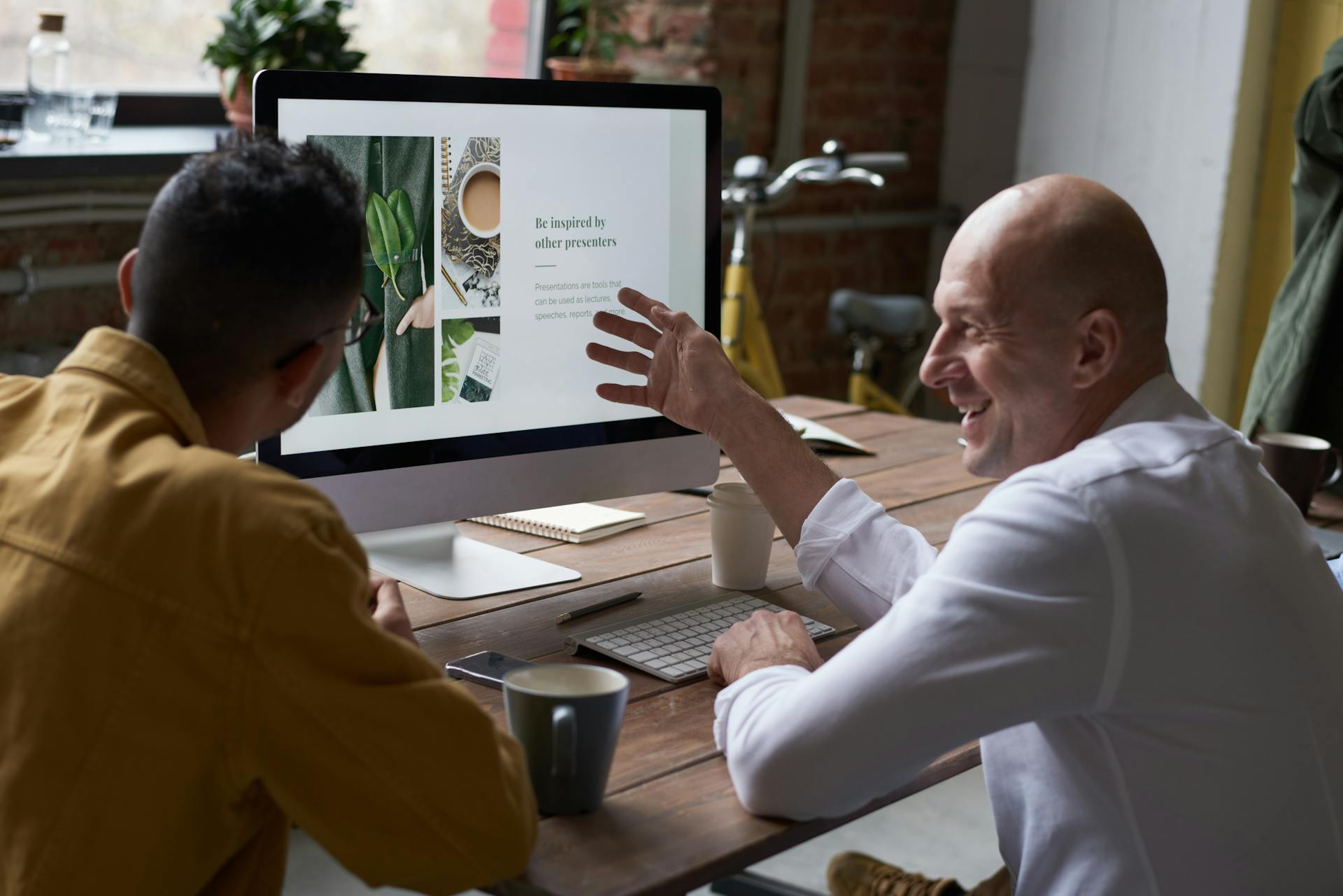Small business owner collaborating with a designer reviewing work on screen