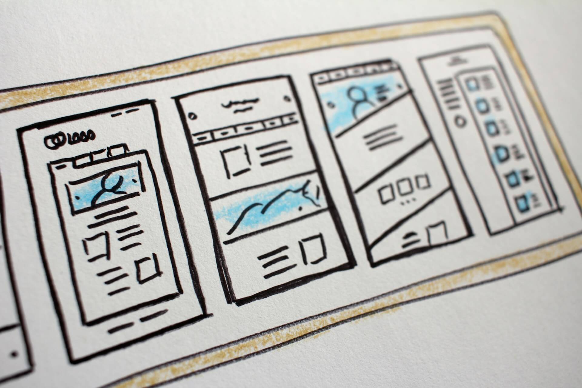 Hand-drawn website wireframe sketch in a notebook with pencil and coffee
